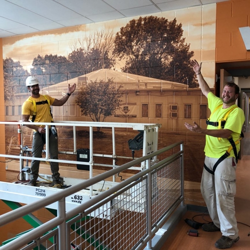 Cinderblock wall graphics with two-man posing for a picture