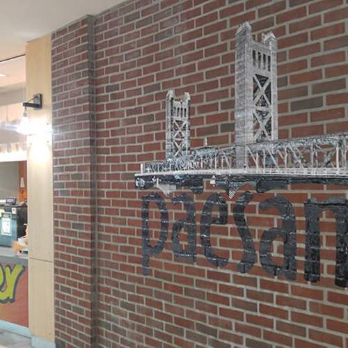 Paesanos sign on the brick wall with a store by the side