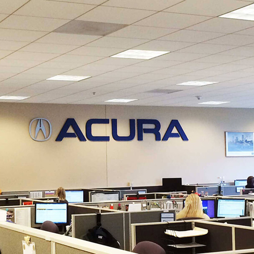 Accura logo on the wall of the office with employees working