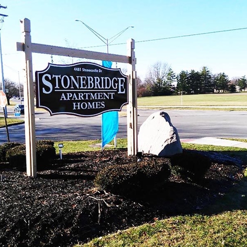 Stonebridge Apartment signage on the side of the road with rocks and plants by the side