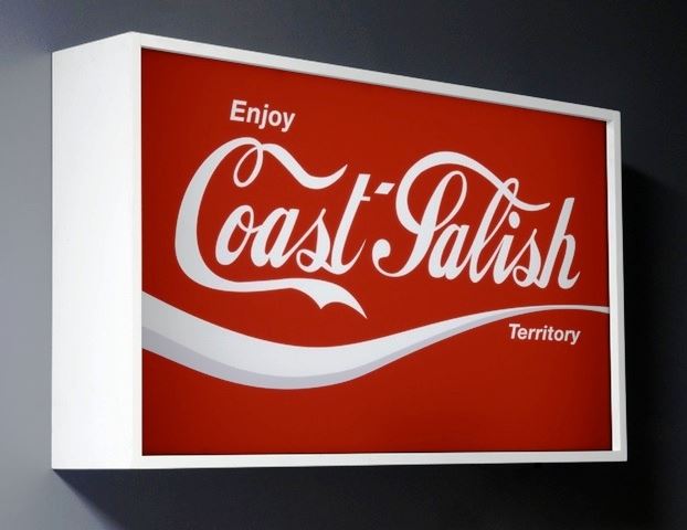 A Coast Salish sign is designed in the Coca Cola font and style