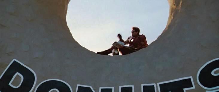 A clip from an Iron Man movie with Iron Man sitting inside of the donut sign