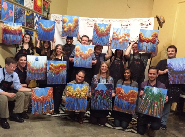 A team poses with paintings they painted together