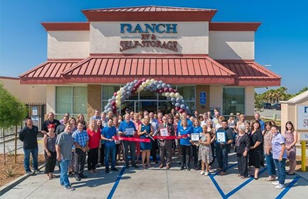A group of employees stand outside of a business's grand opening