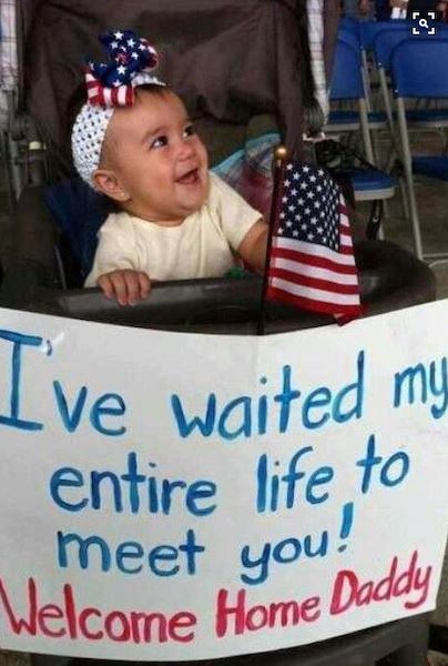 A baby girl has a sign reading "I've waited my whole life to meet you"