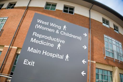 A sign outside of a hospital shows directions for different departments
