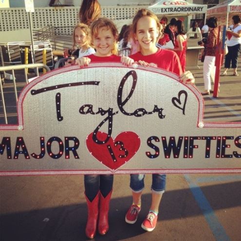 Fans of Taylor Swift hold up a custom illuminated sign for the artist