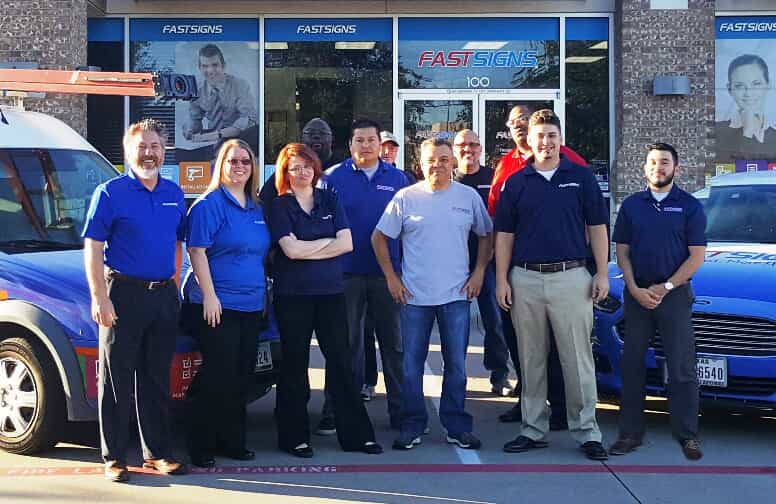The team at FASTSIGNS South Arlington poses by their storefront