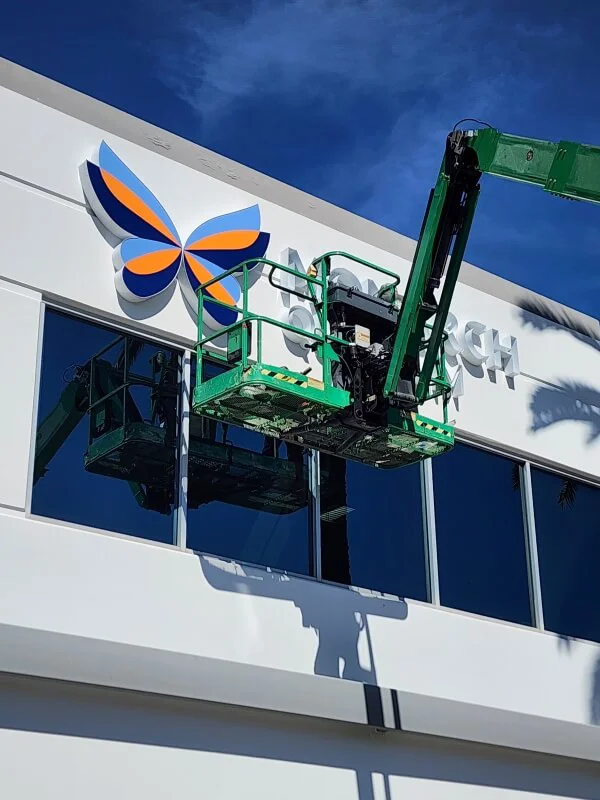 An image of the Monarch channel letter and butterfly logo being installed on a building's exterior.