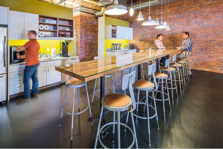 a kitchen has bright yellow walls and brick along other walls