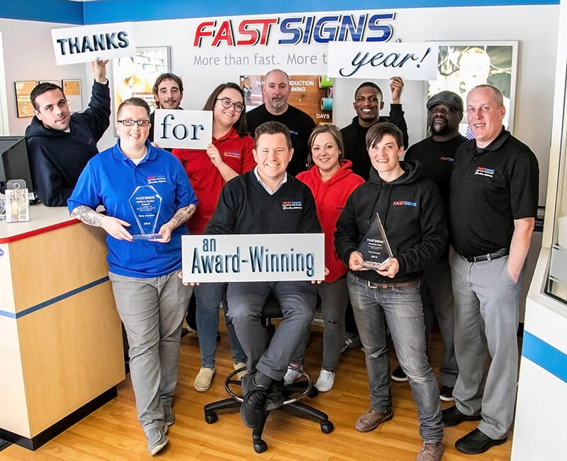 team image of fastsigns columbia, md holding signs saying thanks for an award-winning year
