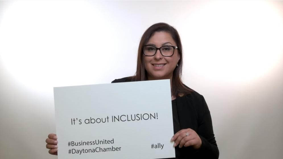 woman holding sign that reads 'it's about inclusion'
